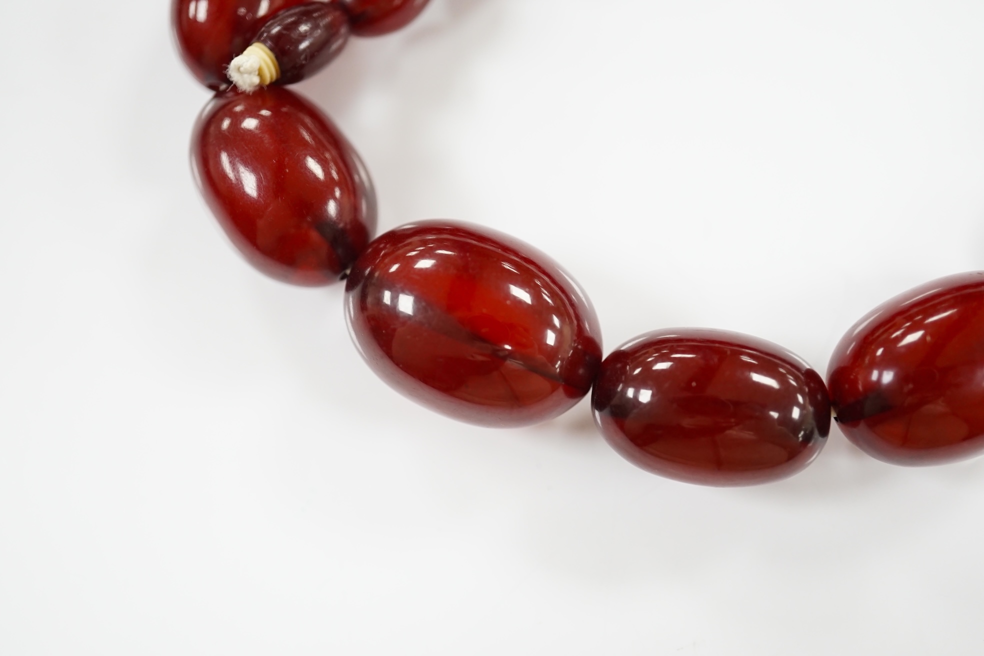 A single strand graduated oval simulated cherry amber bead necklace, 38cm, gross weight 41 grams. Condition - poor to fair